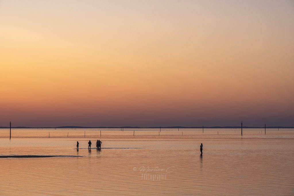 Silhouettes de baigneurs à marée basse au coucher du soleil, Bassin d'Arcachon