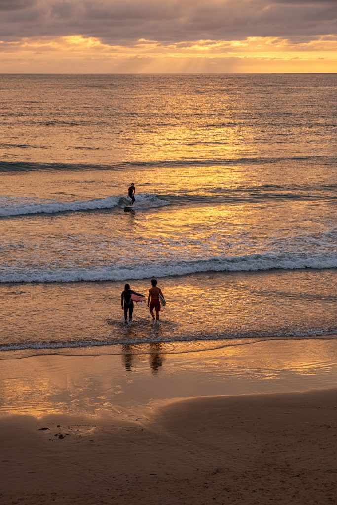 Trois surfeurs au coucher du soleil sur l'océan doré, Côte des Basques